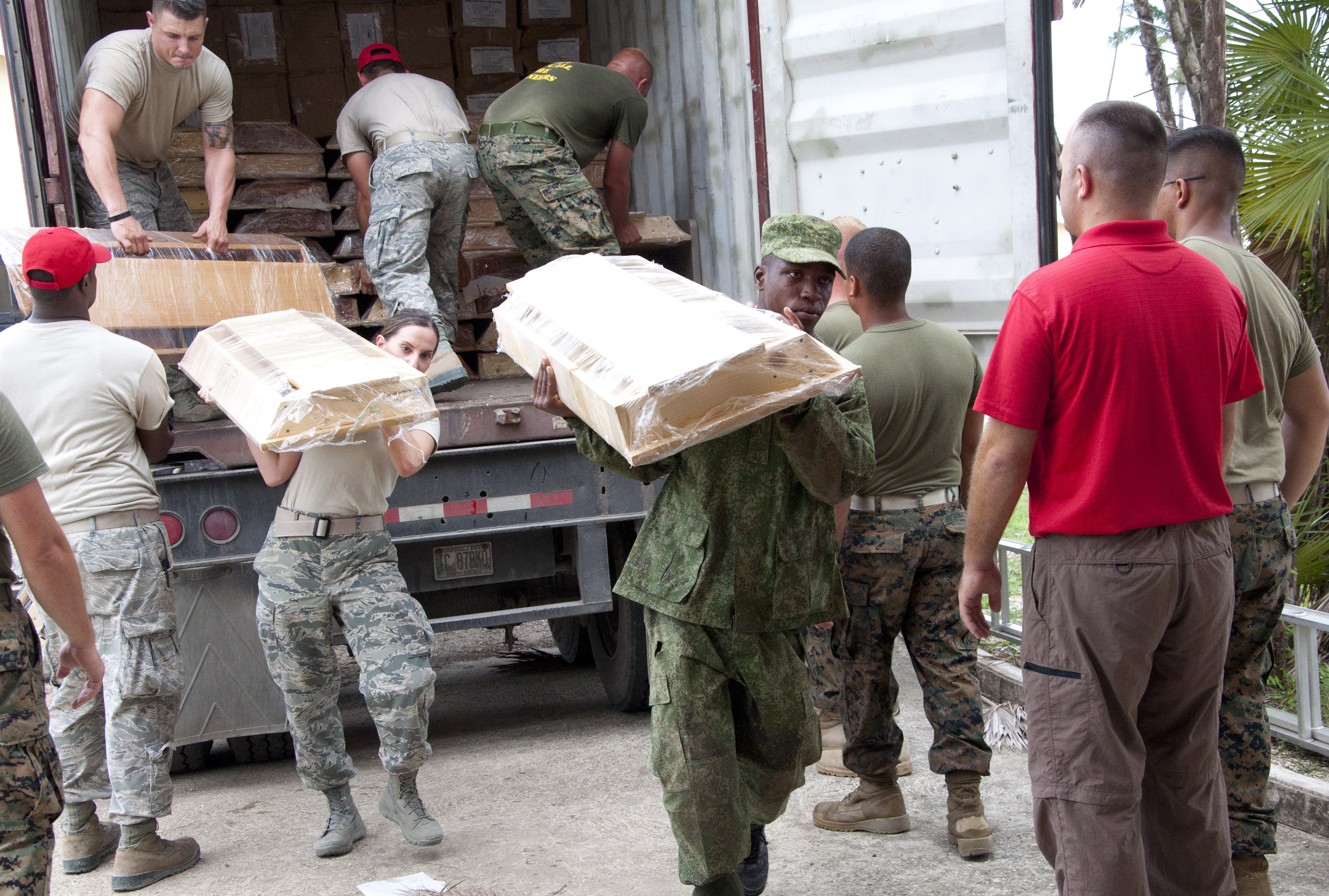 Belize Defence Force & U.S. military members offload school supplies and furniture June 2, 2014, at the BDF Price Barracks in Ladyville, Belize. The Midwest Mission Distribution Center based out of Chatham, Ill., donated the supplies.